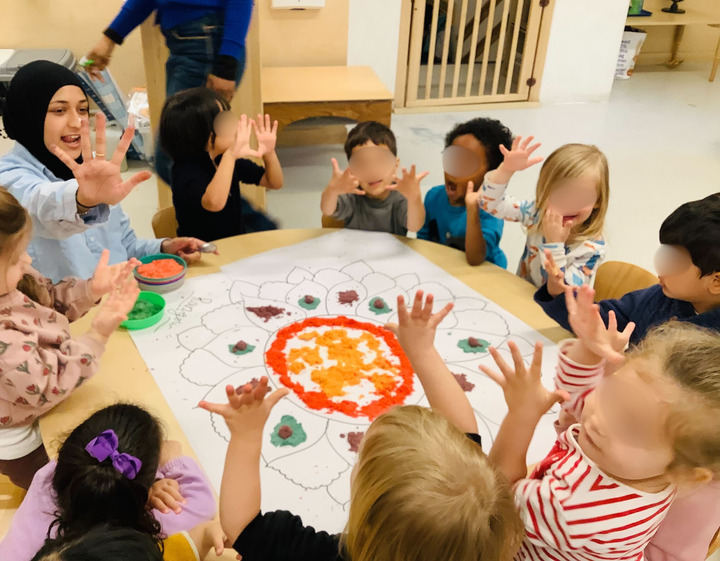 Children and a teacher creating colorful rangoli patterns together as part of Indian cultural activities