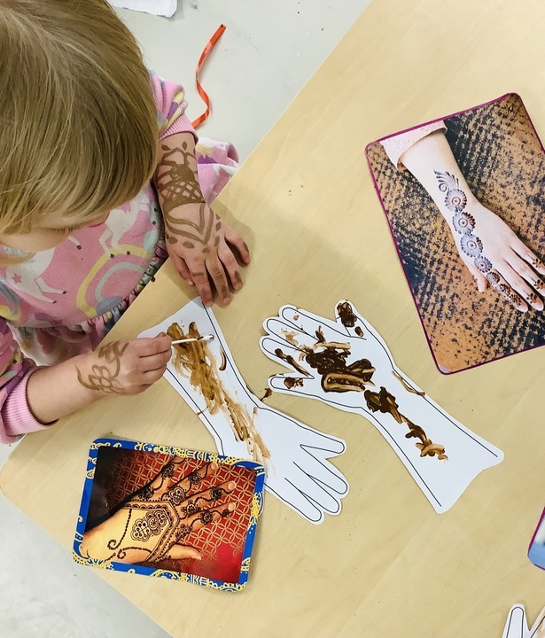 Children and a teacher doing mehndi art together as part of Indian cultural activities